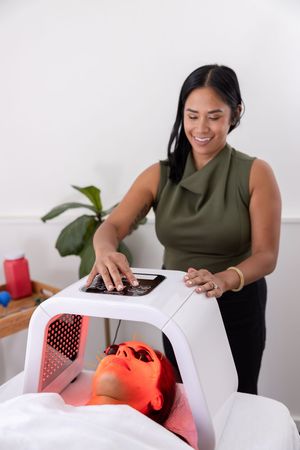 woman acupuncturist branding photo in Issaquah, WA with client acupressure treatment using red light therapy on face of woman during session
