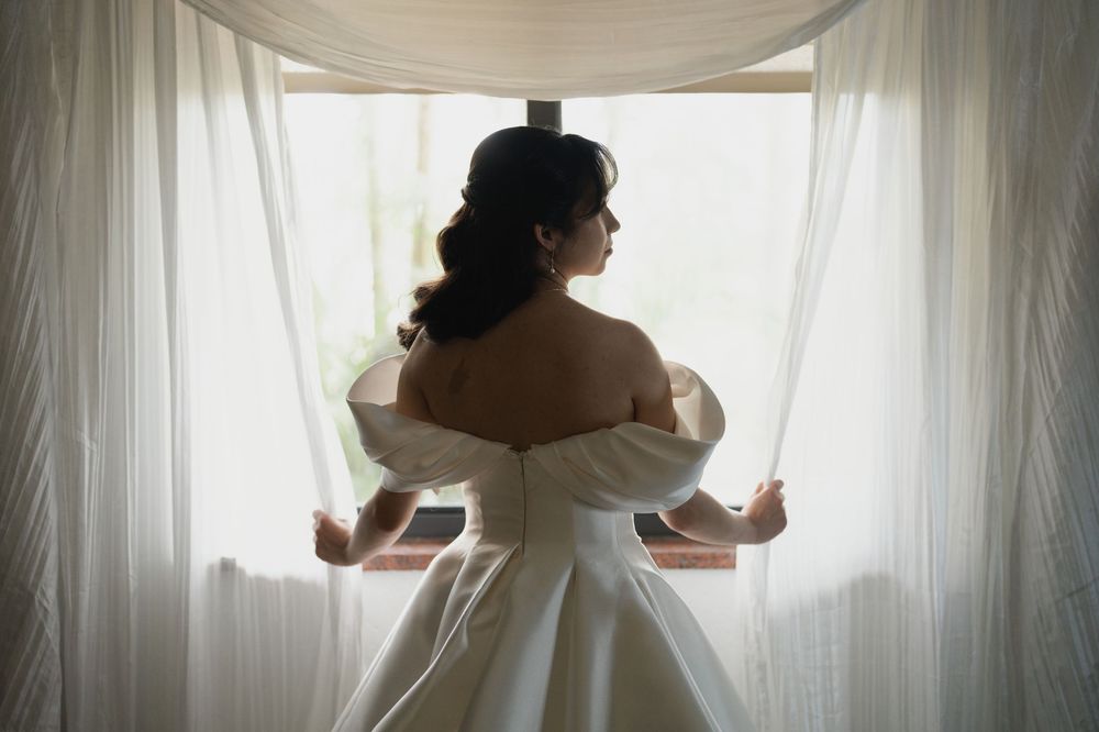 A bride in a white wedding dress stands against sheer curtains in a series of silhouetted poses.
