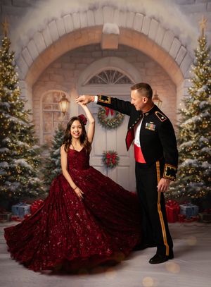 A couple in formal attire, with a burgundy sequined gown and military dress uniform, dancing in front of holiday decor.