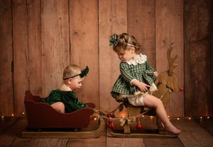 A baby in green romper poses in four sequential shots against a rustic wooden backdrop.