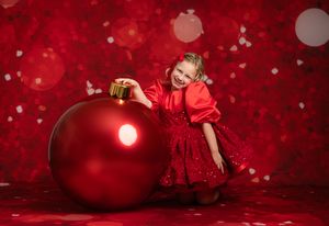 Red Christmas ornament and decorative elements against a festive burgundy background with glowing bokeh lights.