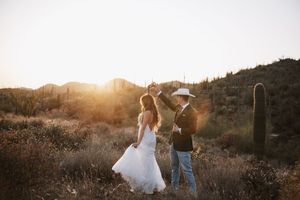 Bride and groom dancing at sunset in the desert.