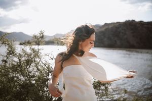Bride standing on a hill with the lake and sun setting behind her.