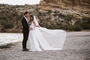 Bride and groom on the beach with brides veil blowing in the wind.