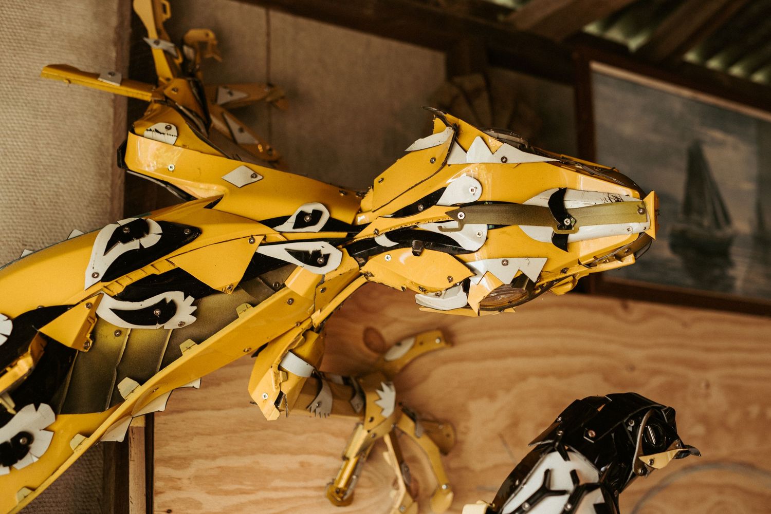 Yellow metal sculptures displayed against wooden wall in artist studio.
