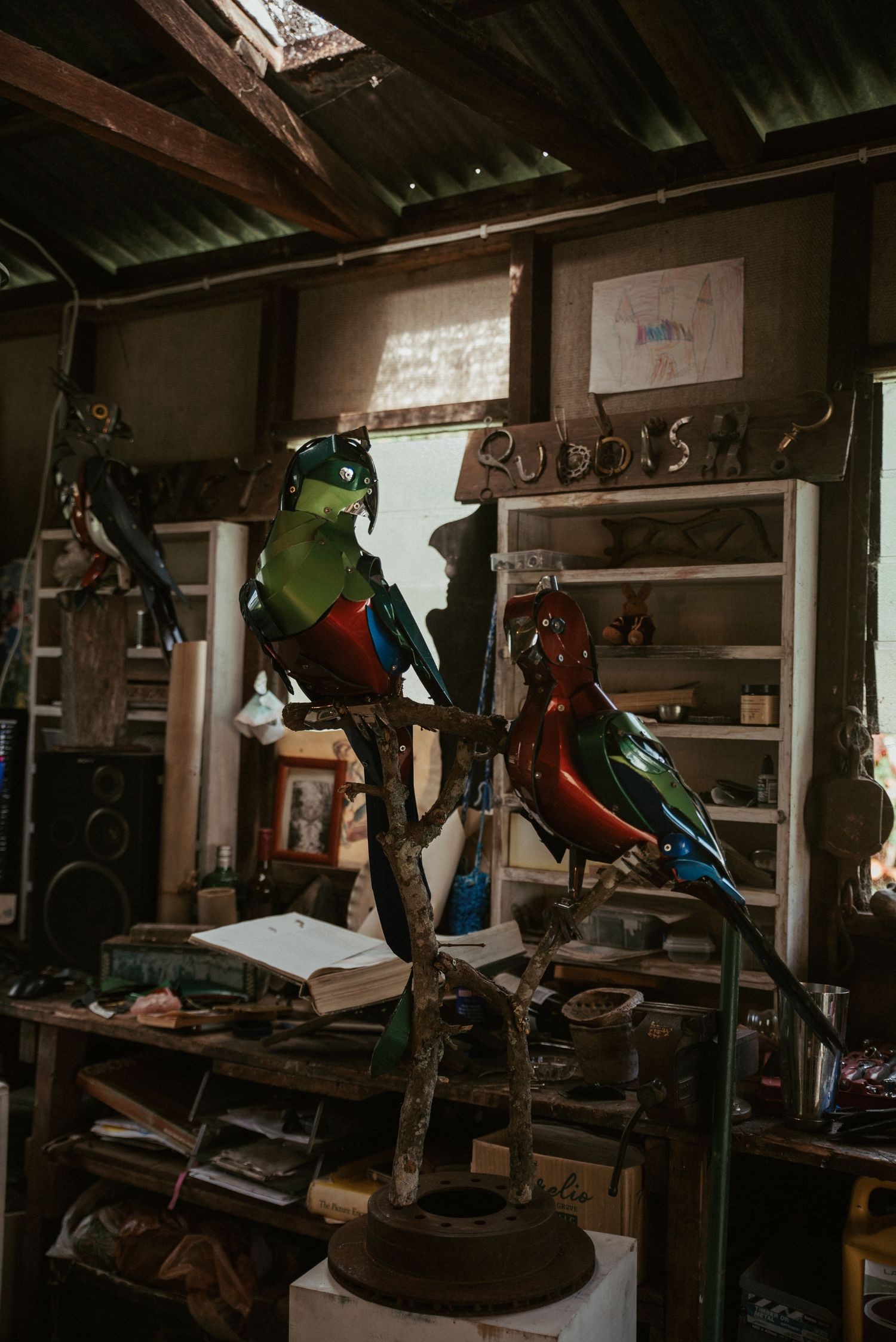 Dark workshop interior with various tools and equipment hanging on walls and shelves.