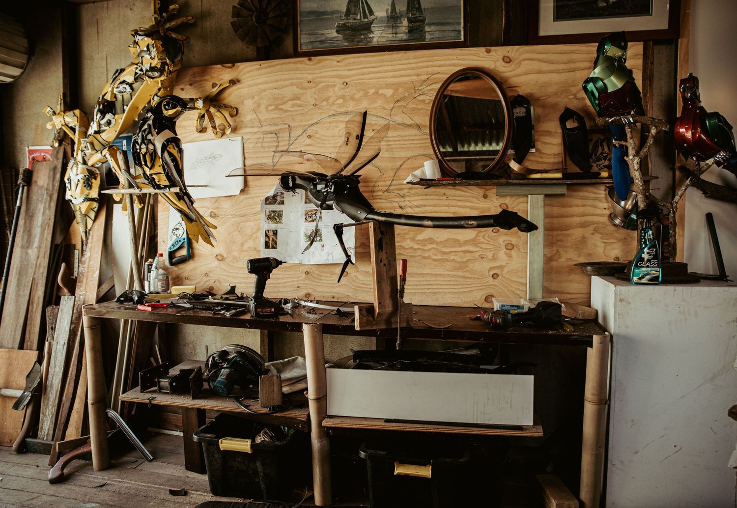 Rustic workshop interior with wooden walls displaying framed artwork and tools.