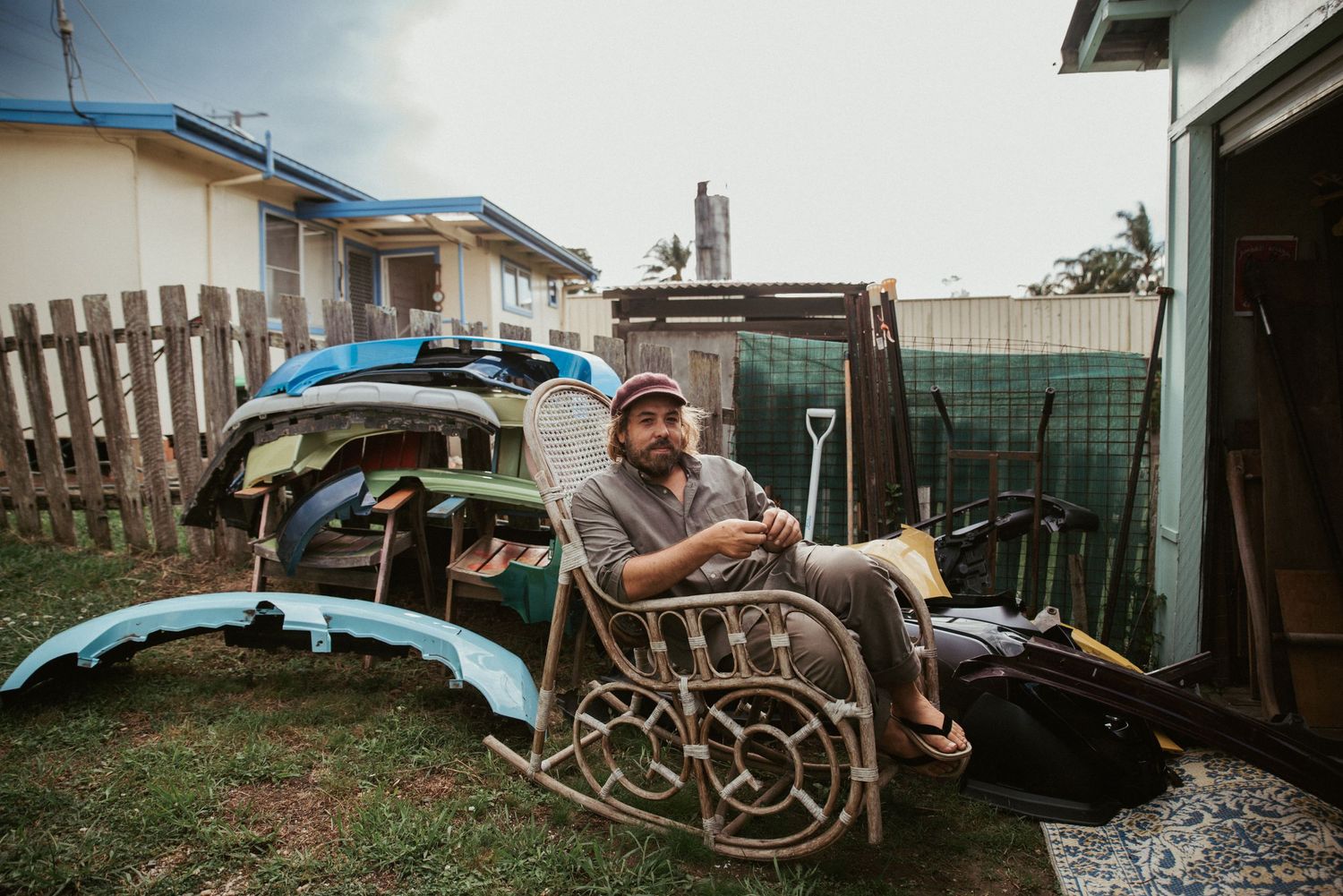 Rustic backyard scene with scattered furniture and equipment under cloudy skies.