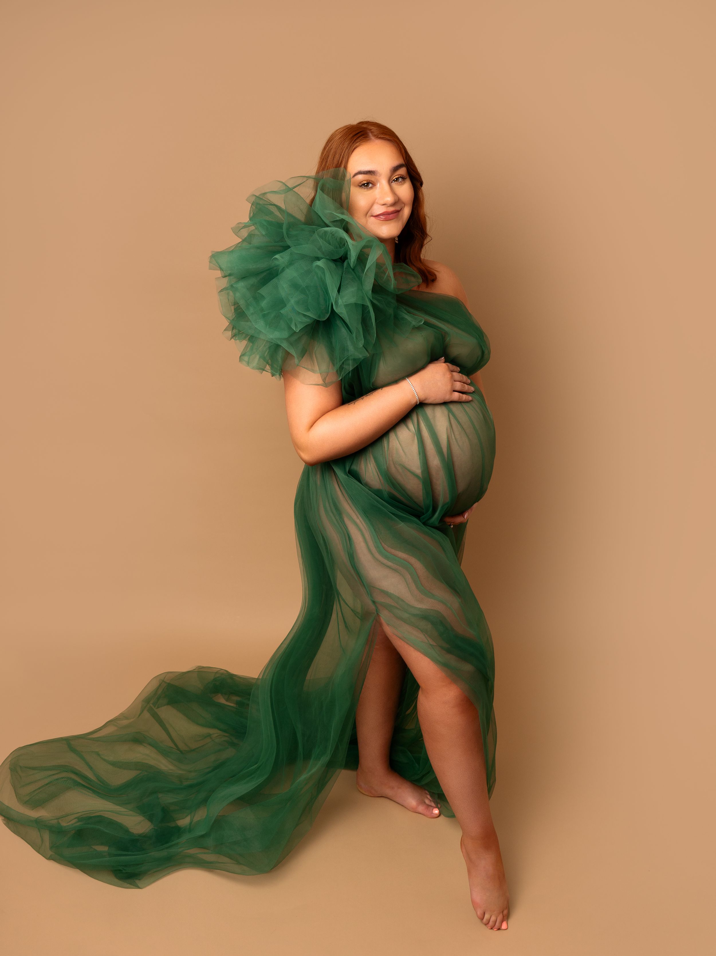 beautiful pregnant lady in green maternity gown holding bump at photoshoot by newborn photographer in doncaster.