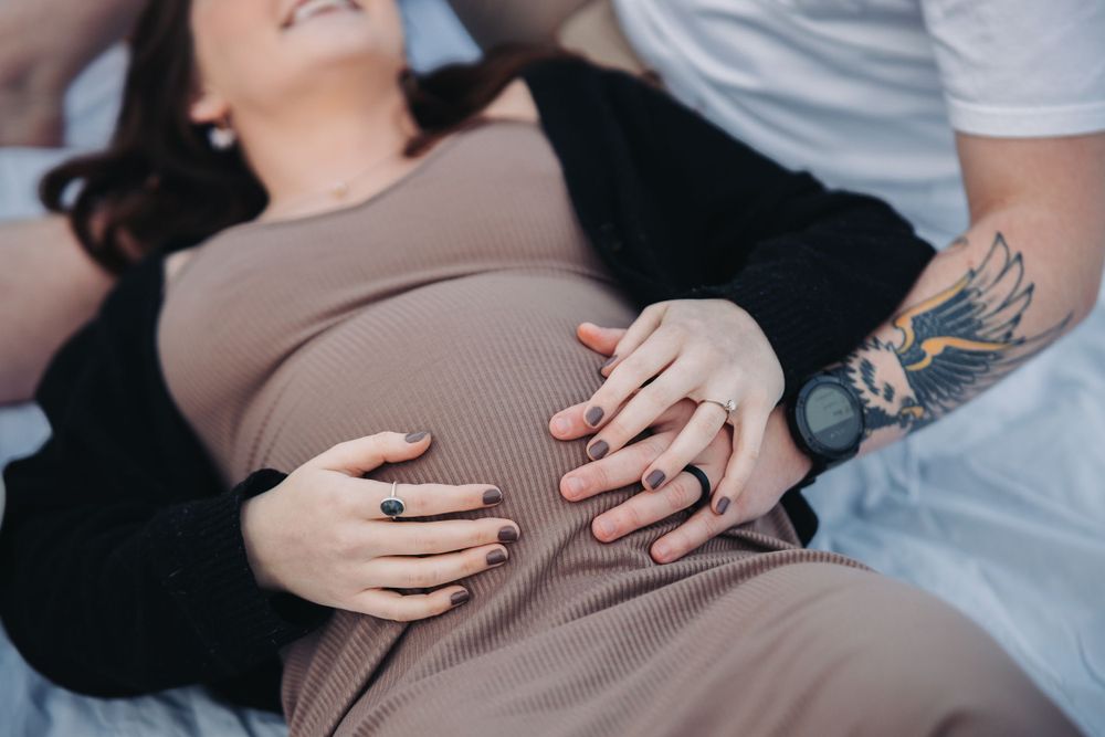 pregnant woman and man lie on the ground in the Saltese Uplands, surrounded by natural scenery and tranquility during their maternity photo