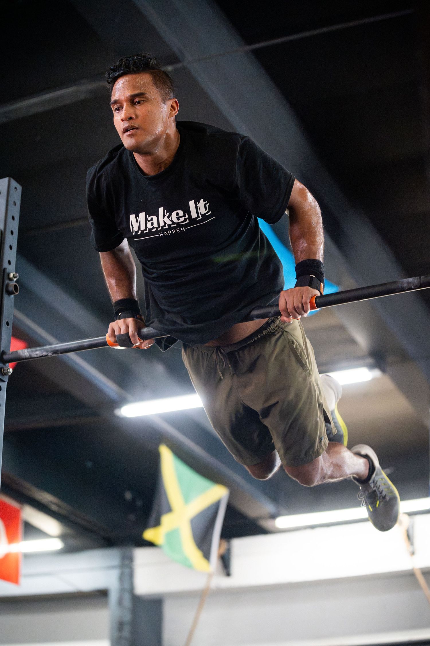 Athlete performing a muscle up exercise on gymnastics rings in a training facility.