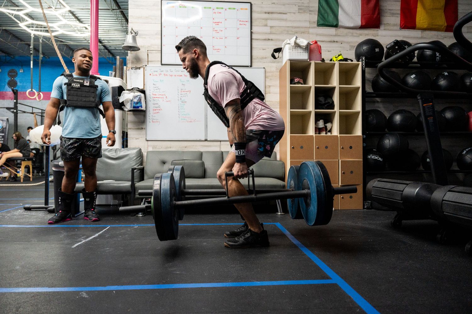 Athletes practicing deadlift technique with barbells in a CrossFit gym.