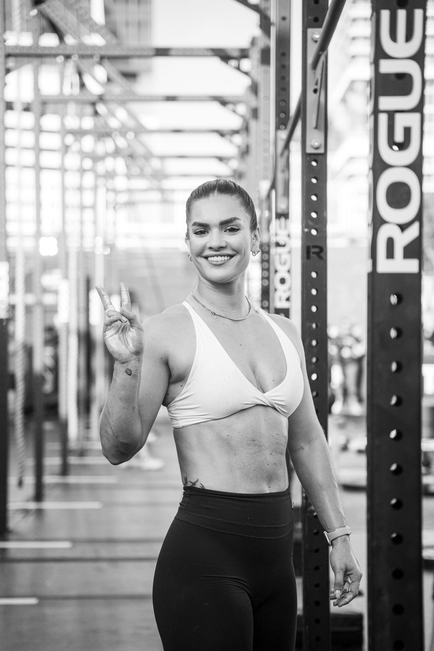Athlete showing peace sign in black and white photo at CrossFit gym.