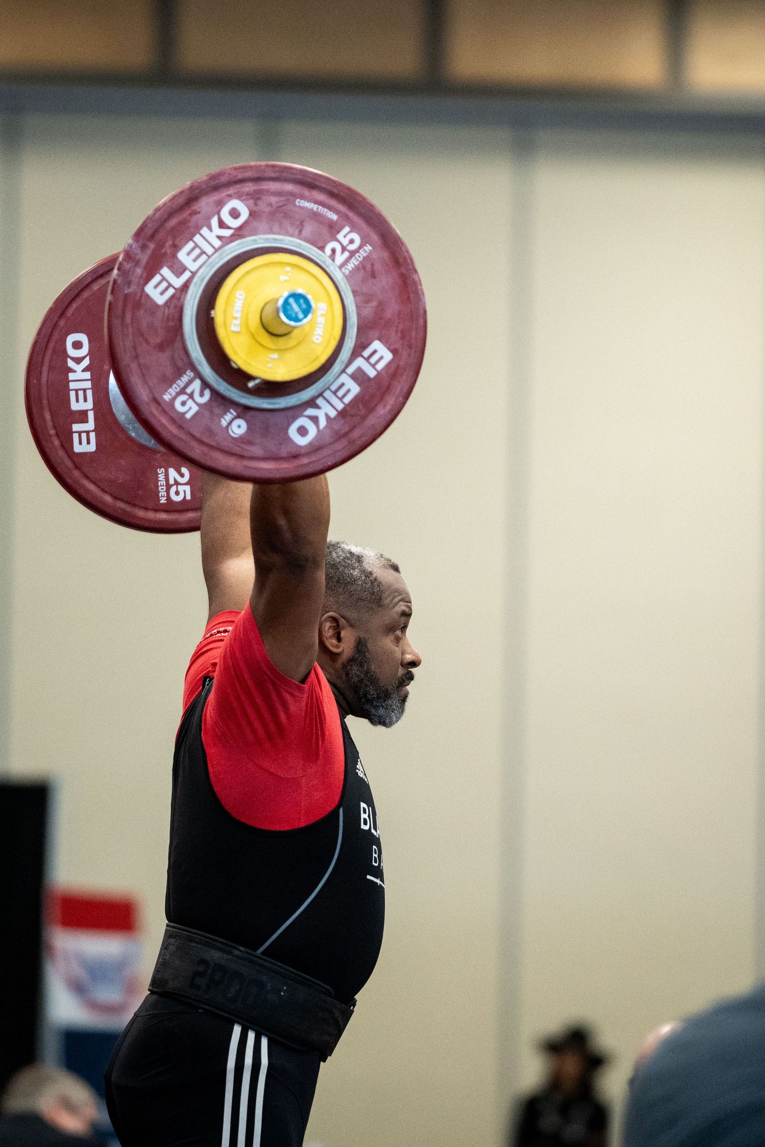 Weightlifter performing an overhead lift with Eleiko competition plates in competition setting.