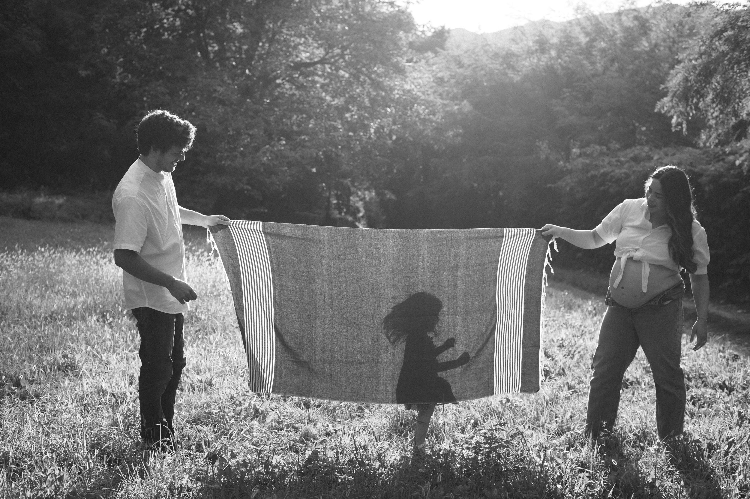 Silhouetted figure tenderly holds newborn baby against bright window background.