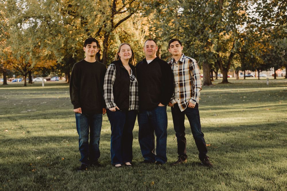 Four people stand together on grass during golden hour autumn photoshoot.
