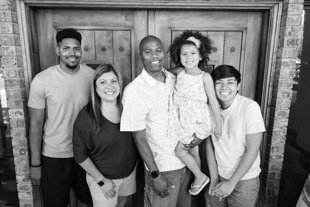Group poses against wooden door background for casual portrait session.