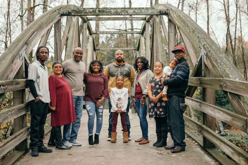 Large group poses together on rustic wooden bridge for outdoor family photo.