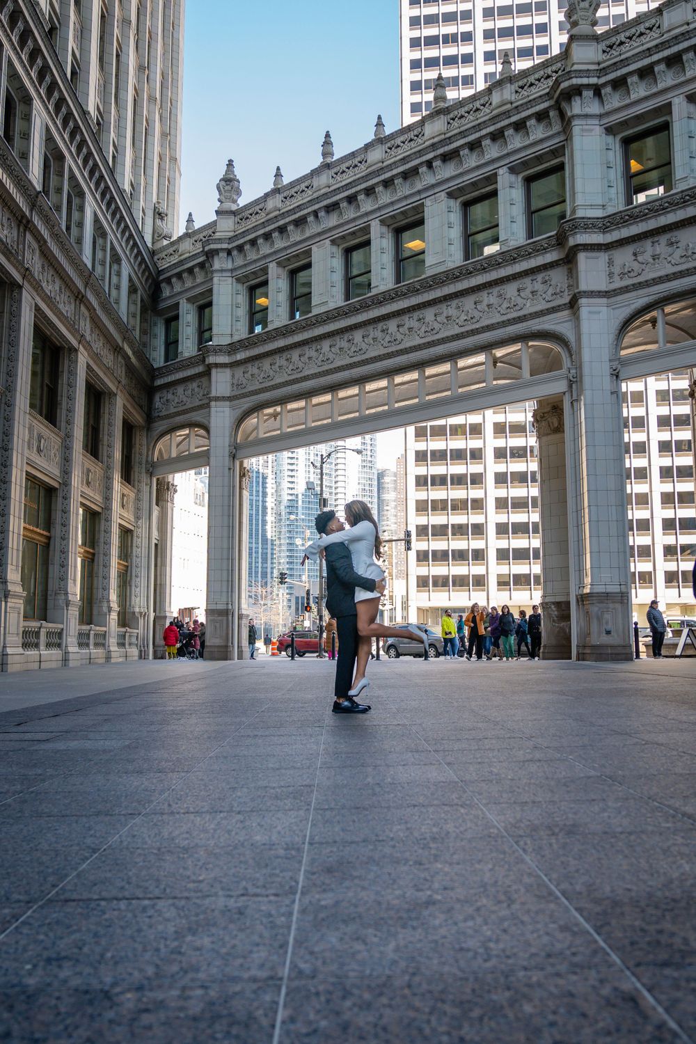 A couple embraces under an ornate architectural archway in downtown Chicago.