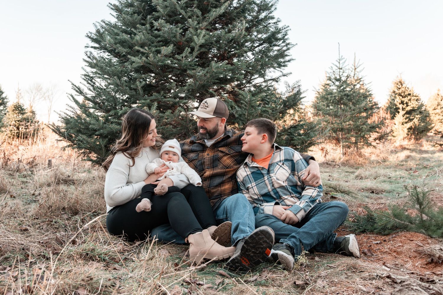 Family sits together at Christmas Tree farm.