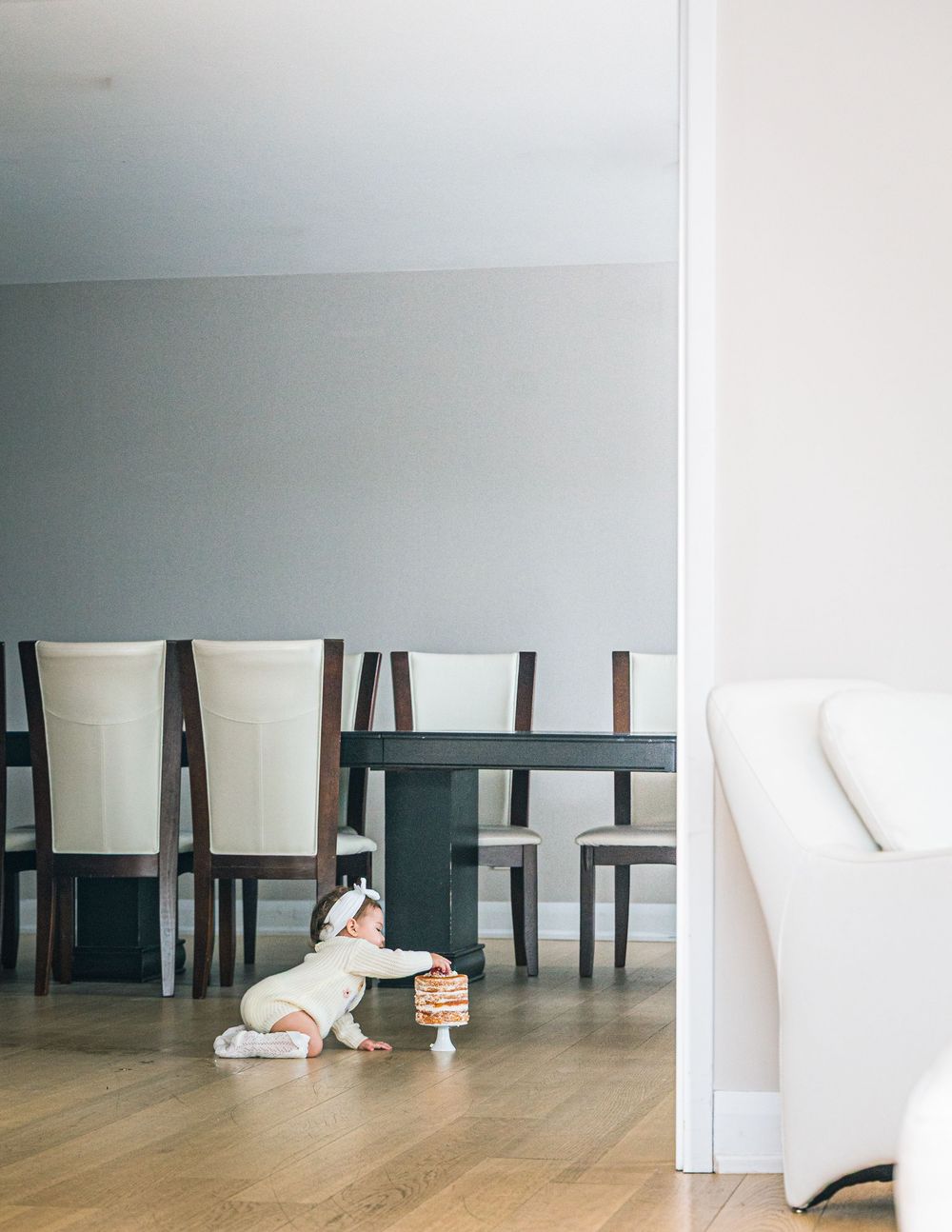 A sequence of photos showing someone lying down and rolling across a wooden floor between white walls and dark chairs.