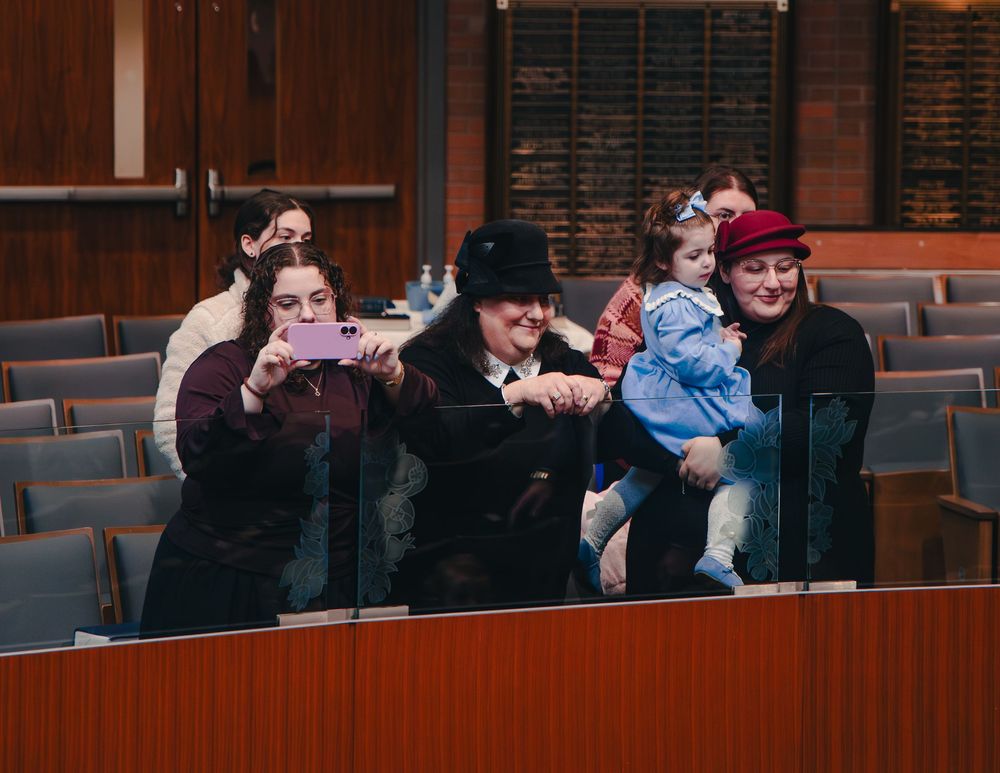 A group of people sitting in a row of theater seats react with laughter and amusement during a performance.