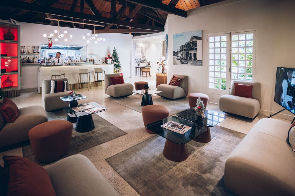 Modern lounge area with beige sectional sofa, brown ottomans, and large windows in a spacious room.