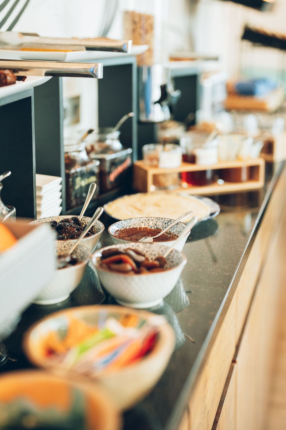 Various bowls with ingredients sit on a blurred wooden counter in a soft-focus photo composition.