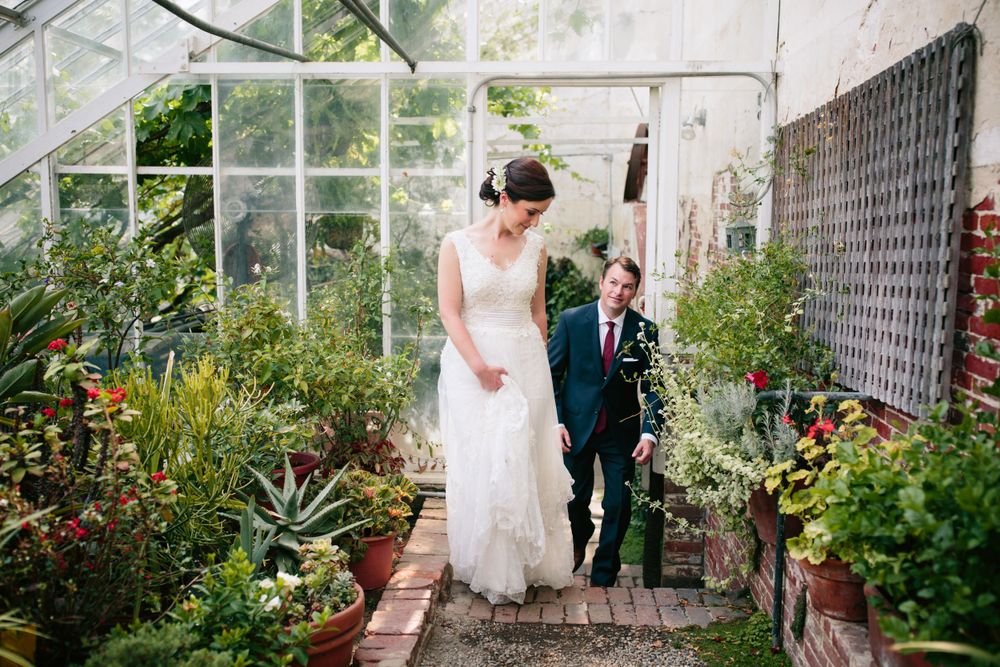 A couple walks through the lush greenhouse at the historic Lyman Estate filled with plants and natural light.