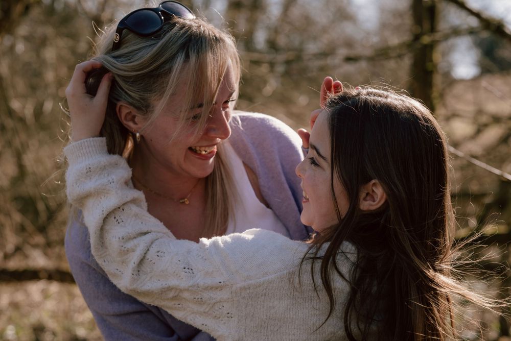 Two people share a joyful moment outdoors on a sunny day, embracing and laughing together in natural light next to Jubilee lake