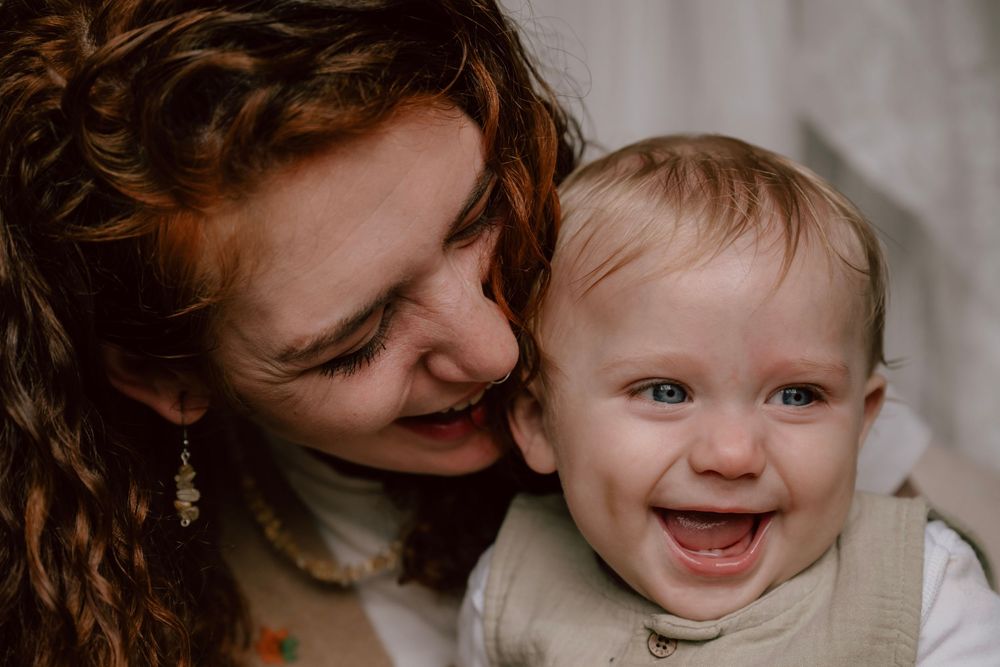 An intimate moment of laughter and bonding between mother and baby, captured in warm, natural lighting.