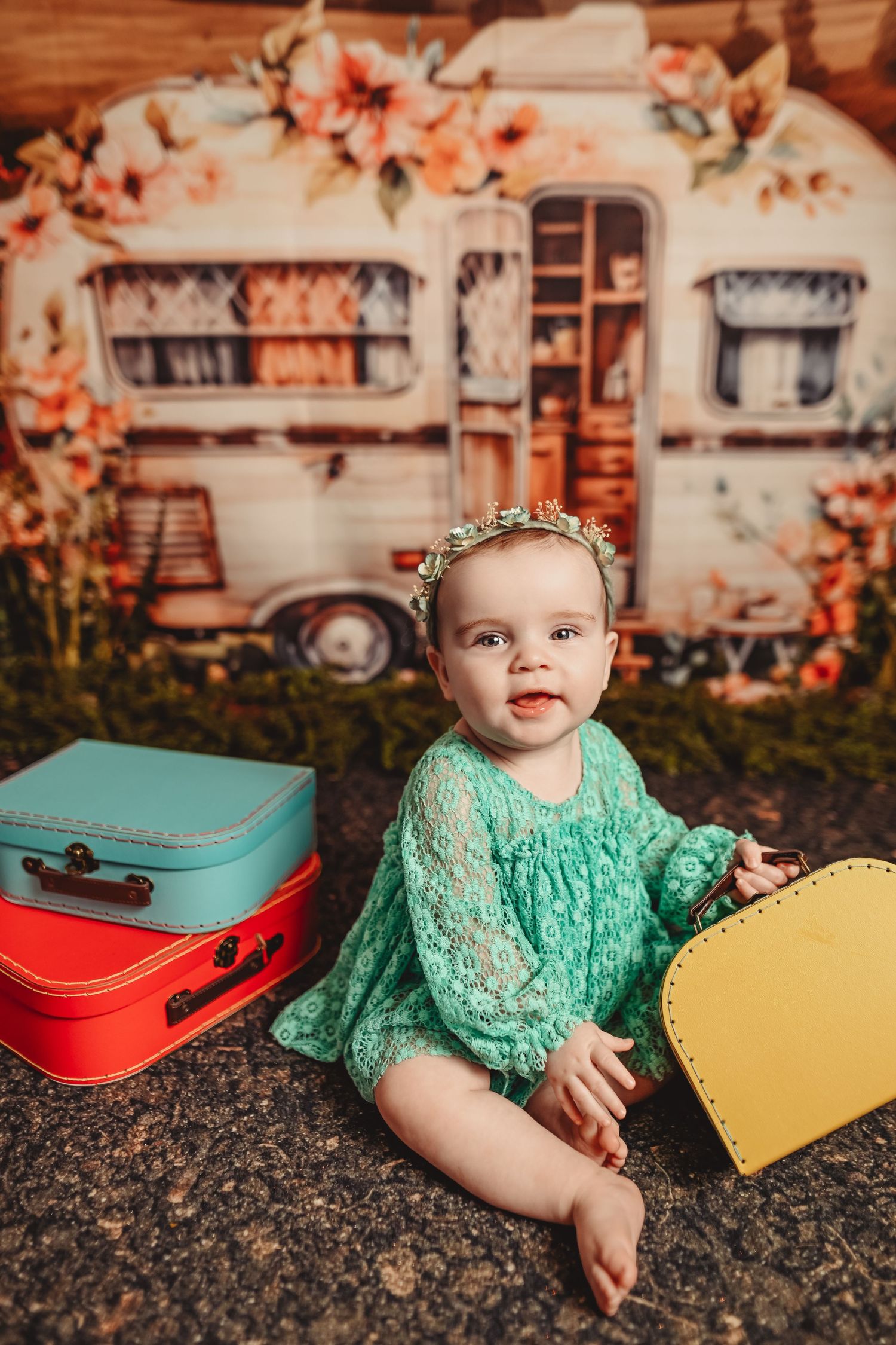 Retro-inspired baby photo with mint dress and vintage suitcases against camper backdrop.