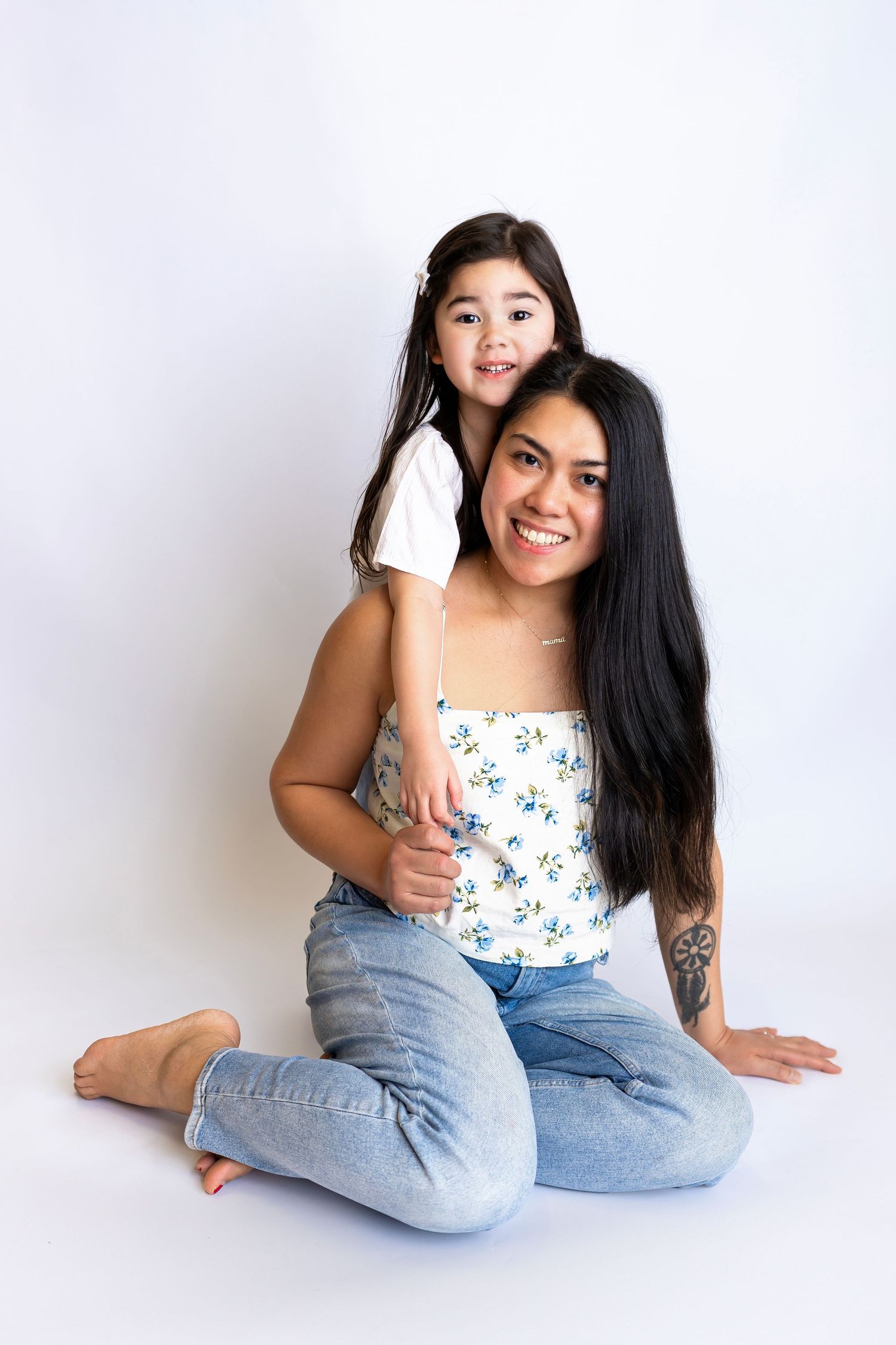 A heartwarming portrait of two people in casual attire sitting together on a white background, sharing a close embrace.