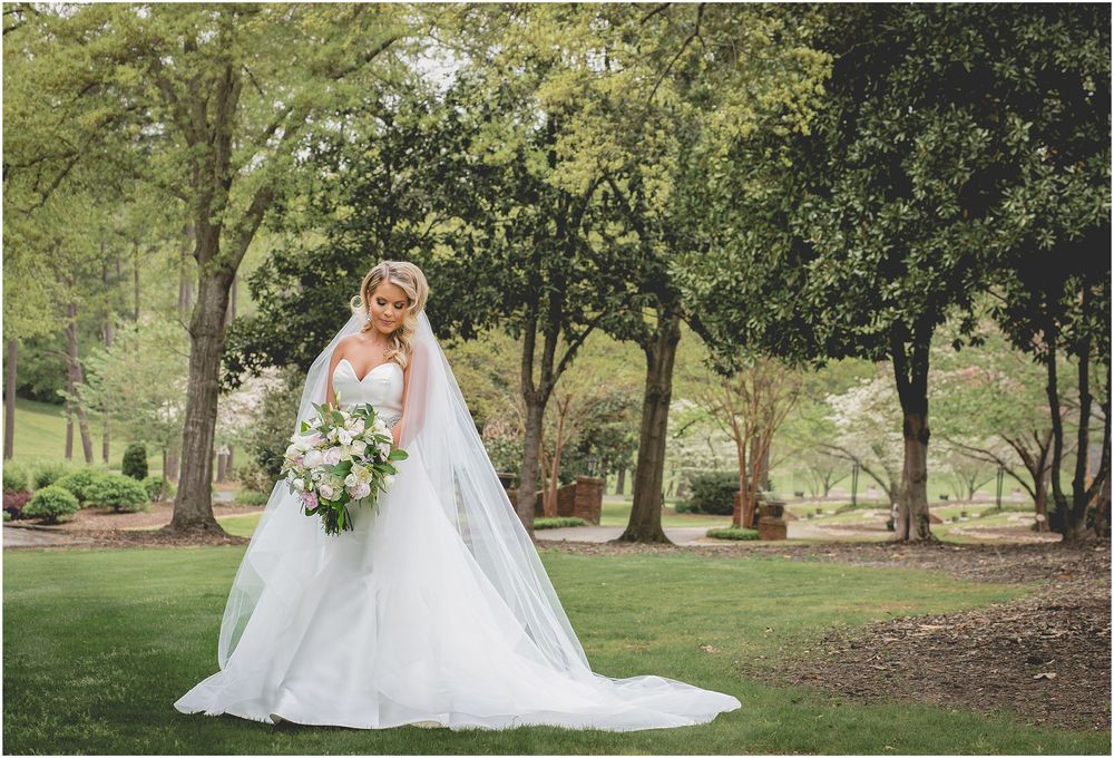A scenic outdoor wedding photoshoot in a lush garden setting with natural greenery and trees.