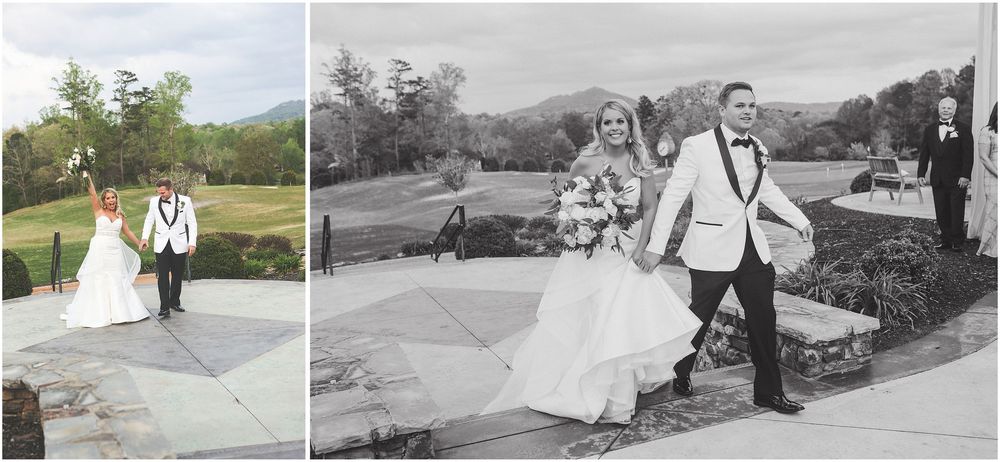 A couple walks joyfully together along an outdoor stone path during a wedding celebration.