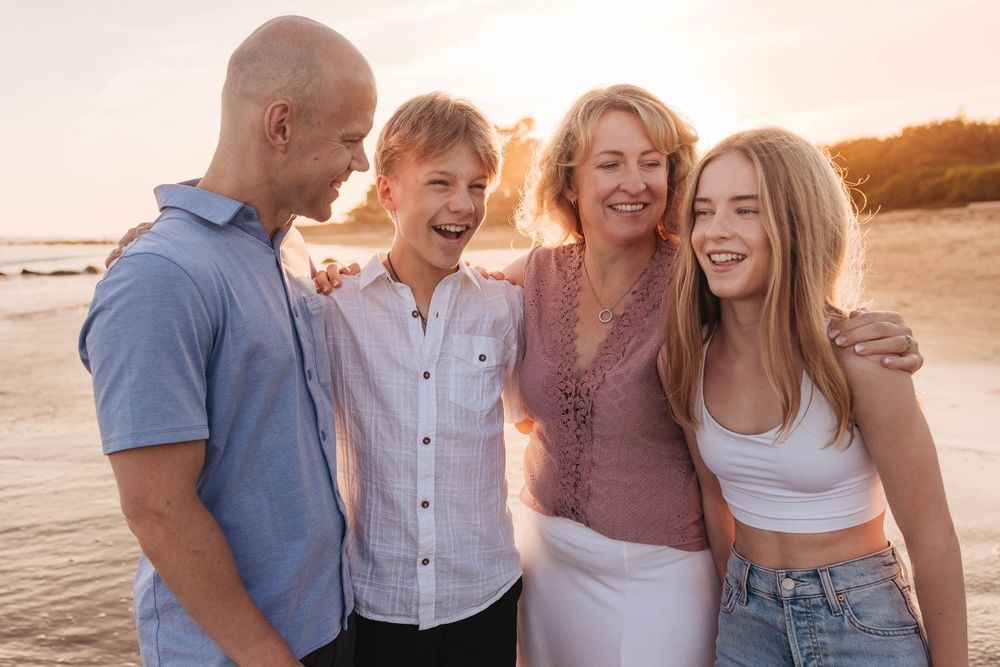 Candid sunset beach portrait of group members laughing together.