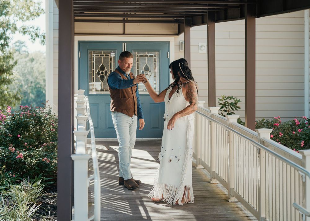 Couple sharing a toast on a charming porch with blue door and flowers.