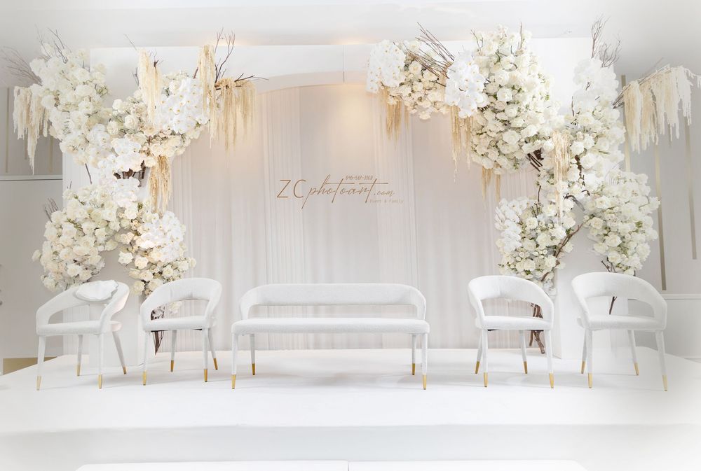 Elegant white wedding reception decor with delicate floral arrangements and crystal chandeliers in a luxurious banquet hall.