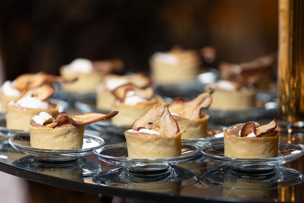 Mini tarts topped with whipped cream and chocolate arranged on glass plates.