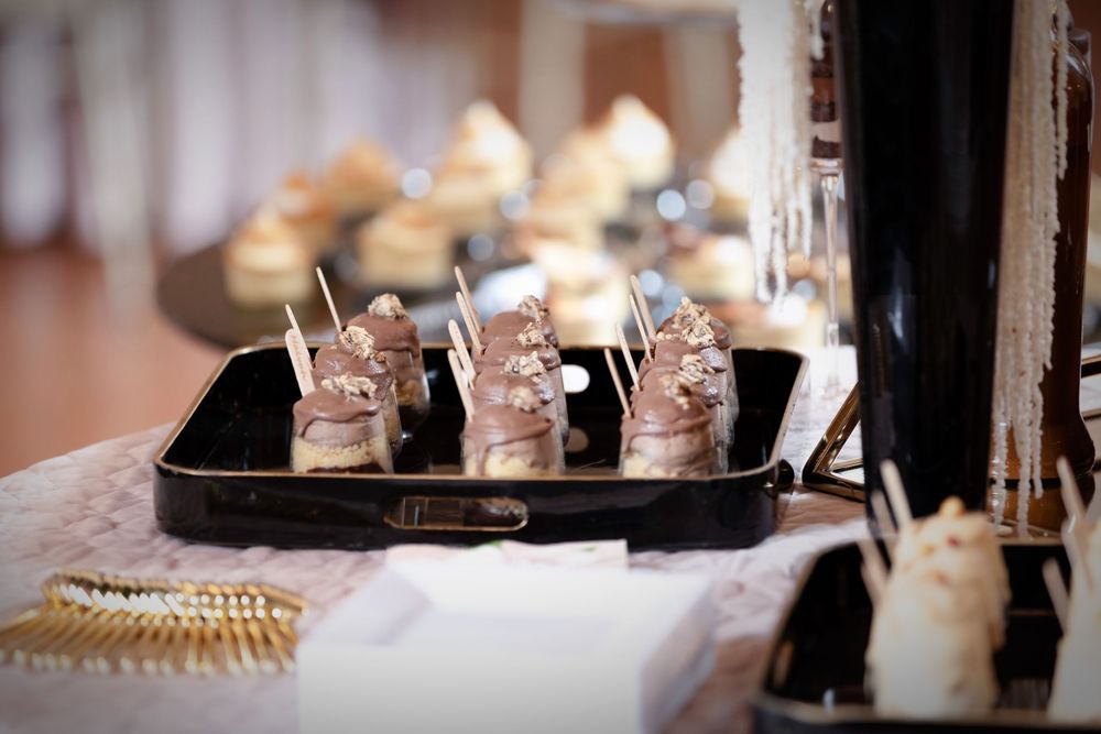 Small dessert shots arranged on a dark serving tray with decorative pearls.
