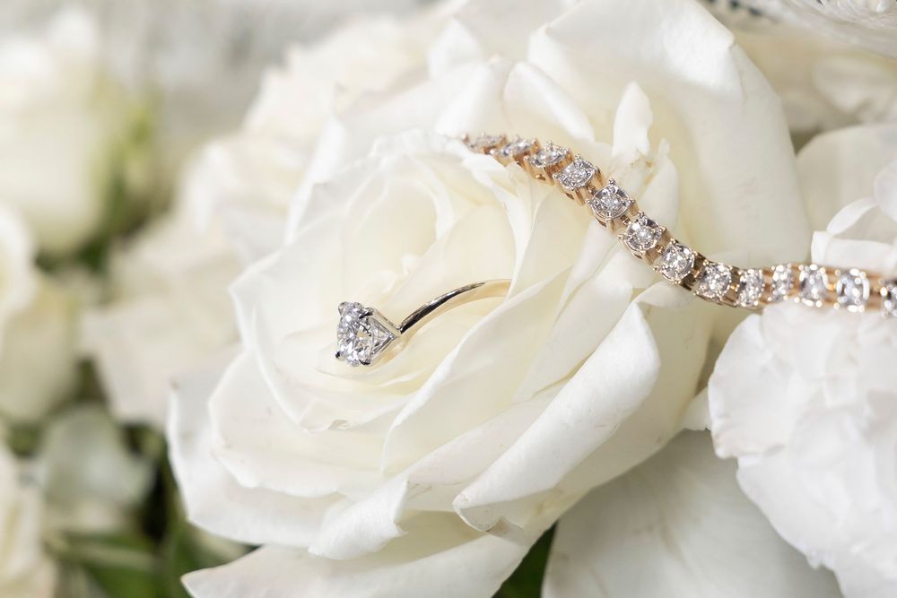 Delicate white roses arranged in a bouquet with sparking diamond jewelry and rhinestone details.
