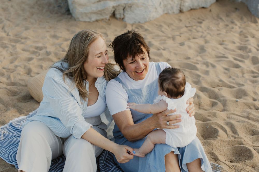Family laughing and having fun together while sitting on sandy beach during sunset.