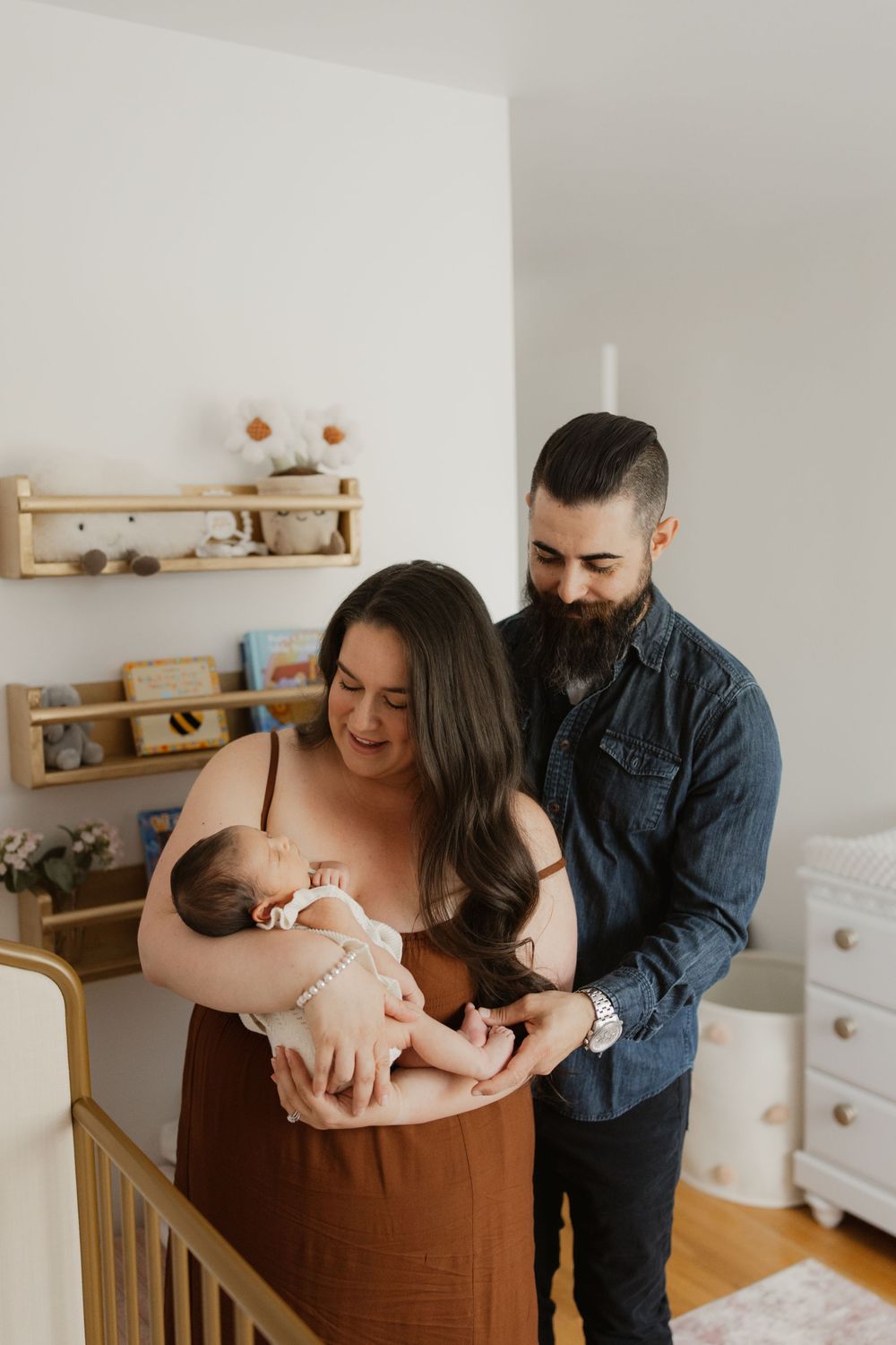 Family photography session in a minimalist nursery with wooden furniture and white walls.