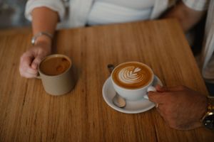 Two coffee cups with latte art on a wooden table.