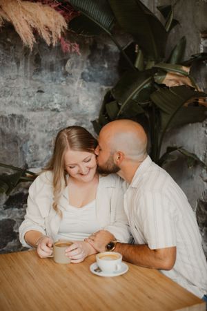 A couple sharing an intimate moment at a rustic cafe table.
