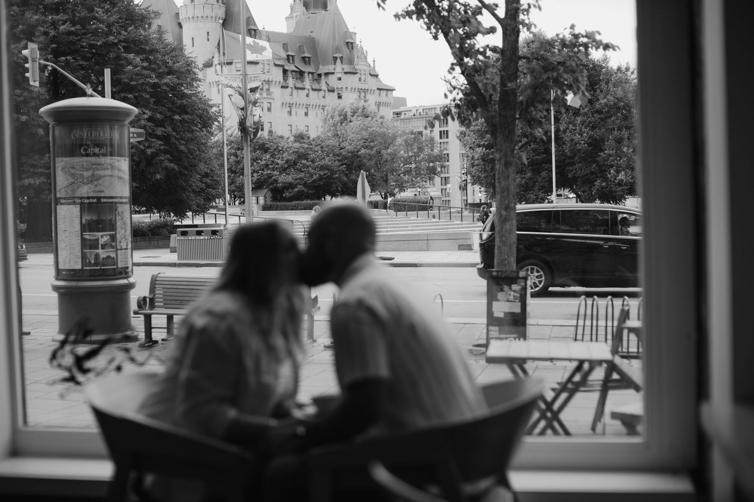 A silhouetted couple sitting by a window with a castle view in the background.