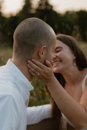 A romantic moment captured between a couple at sunset showing an intimate display of affection and smiles.