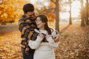 A tender embrace captured during an autumn photoshoot with golden sunlight filtering through trees.