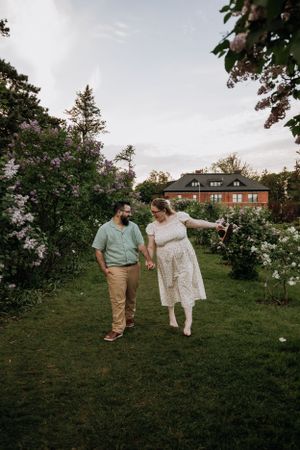 A couple walking hand in hand through a blooming garden at sunset.