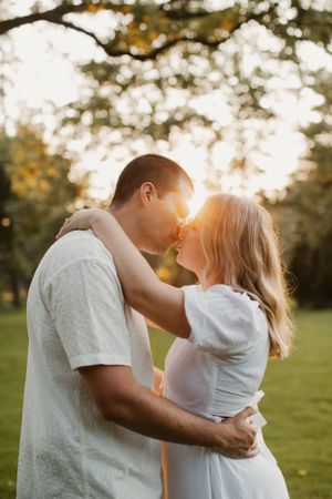 A tender moment between a couple in white clothing against a sun-dappled background.